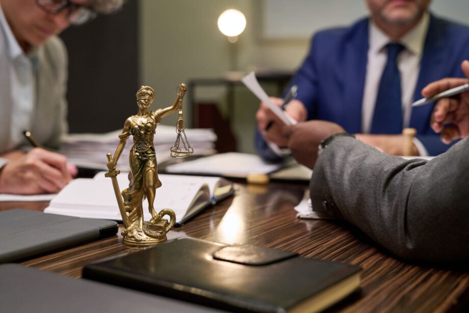 Legal professionals reviewing documents at a conference table with a Lady Justice statue representing attorney consultation for an 18-wheeler accident case in Dallas.