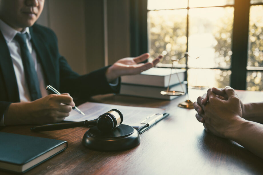 Dallas assault and domestic violence attorney consulting with client with gavel and scales of justice on desk
