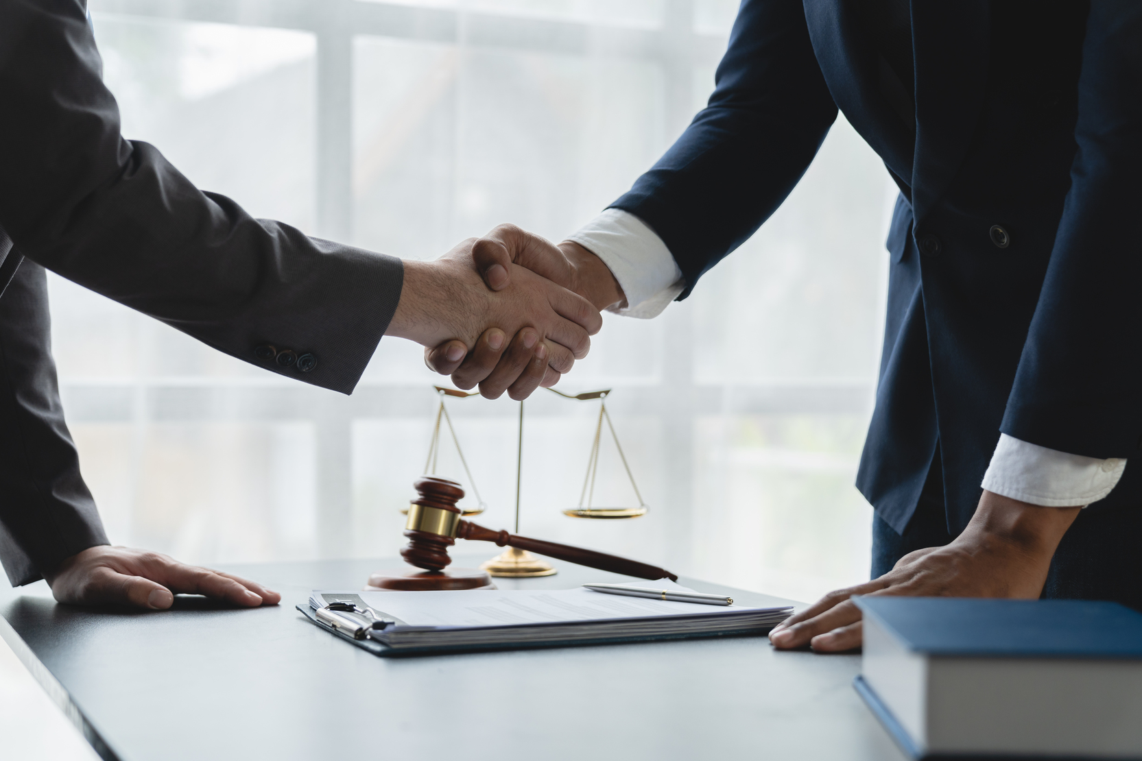 Dallas attorney and client shaking hands after legal consultation with gavel and scales of justice