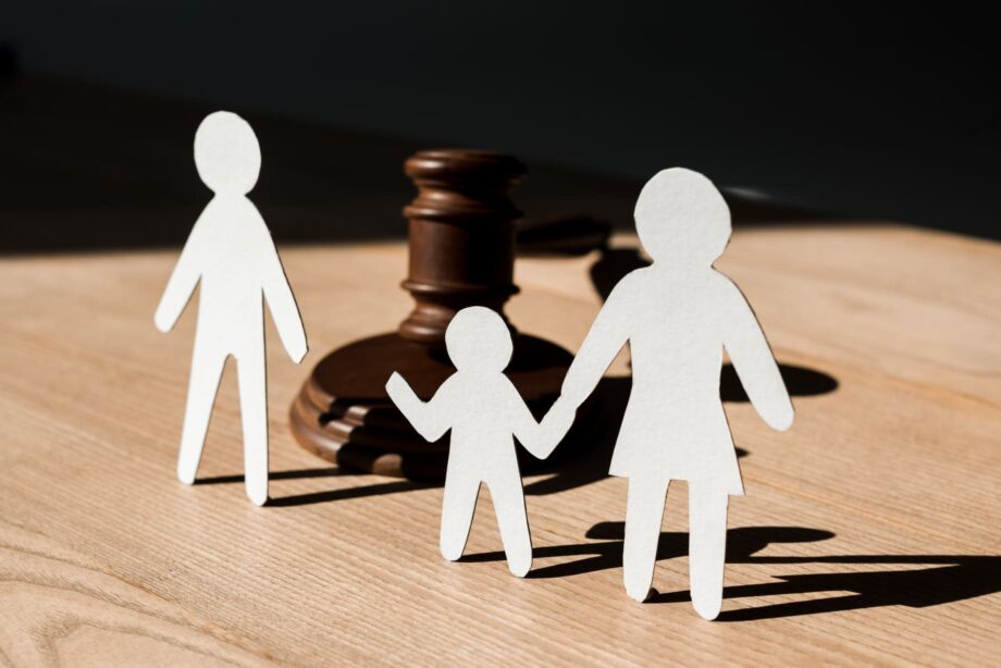 Paper cutout family figures with child between separated parents in front of gavel representing Dallas child custody court proceedings