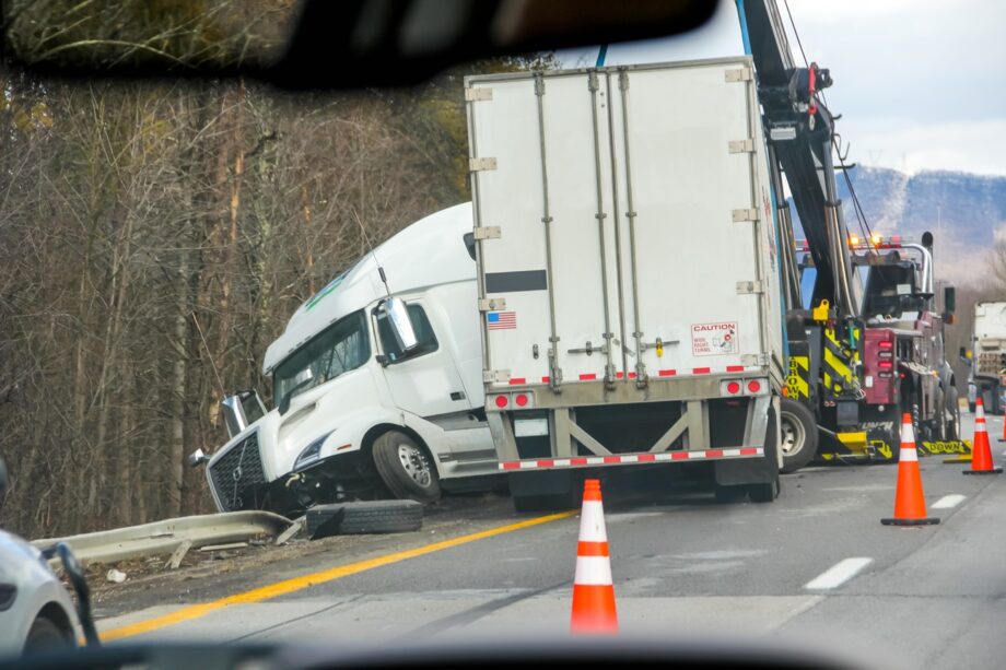 18-wheeler jackknifed off Dallas highway being recovered by tow truck after commercial truck accident