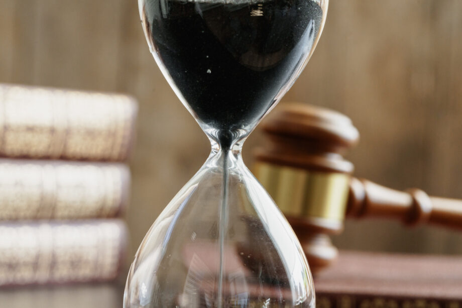 Hourglass next to a judge's gavel and law books representing the timeline of a truck accident lawsuit in Texas
