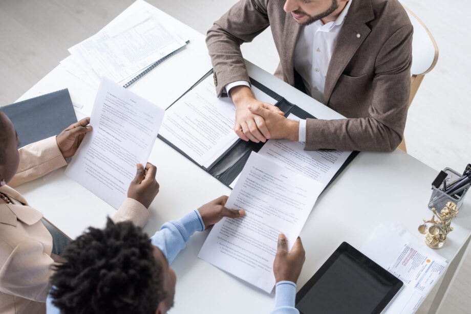 Overhead view of a couple reviewing legal documents with an attorney at a consultation table representing wrongful death damage recovery options in Dallas Texas