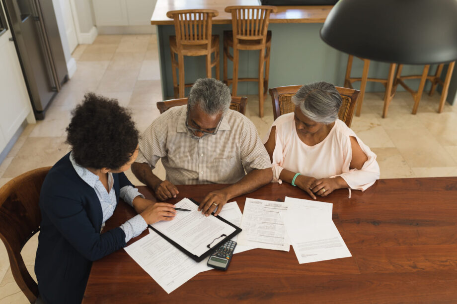 Overhead view of a senior couple reviewing legal documents with a female attorney at a table representing a wrongful death or personal injury consultation in Dallas Texas