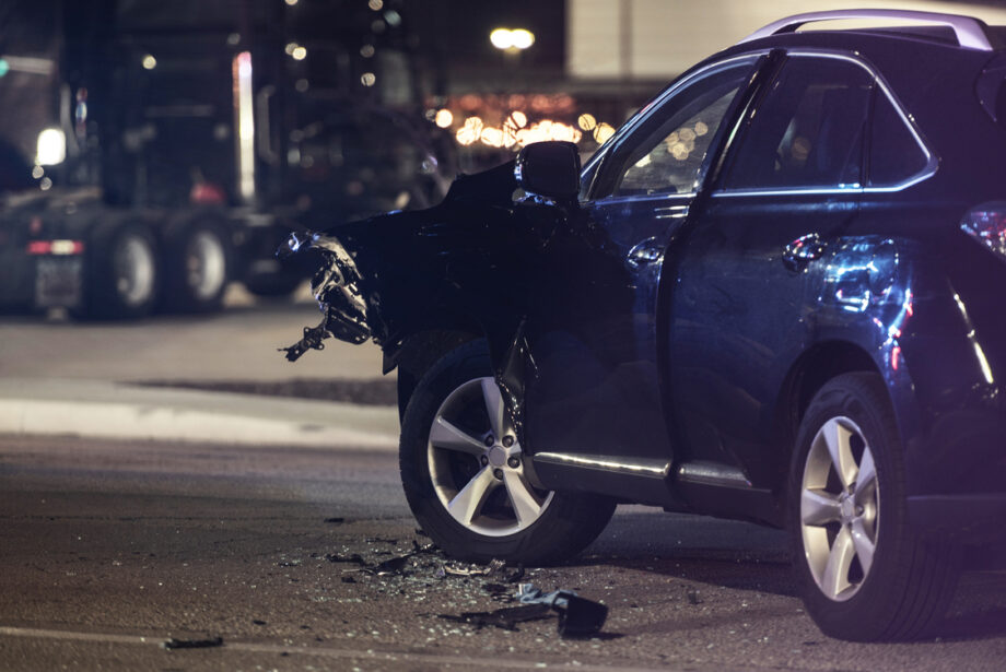 Damaged vehicle with crushed front end after car accident collision on Dallas street at night